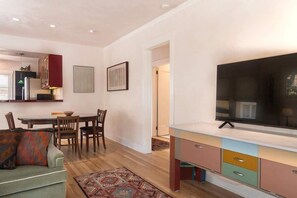 Una sala de estar moderna con comedor, televisor y área de cocina.