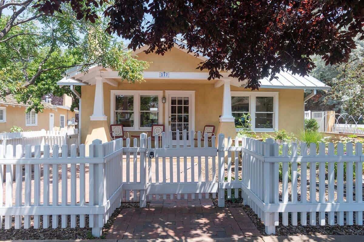 A two-story building with a white picket fence, a number '217' sign, and a brick pathway leading to the entrance.
