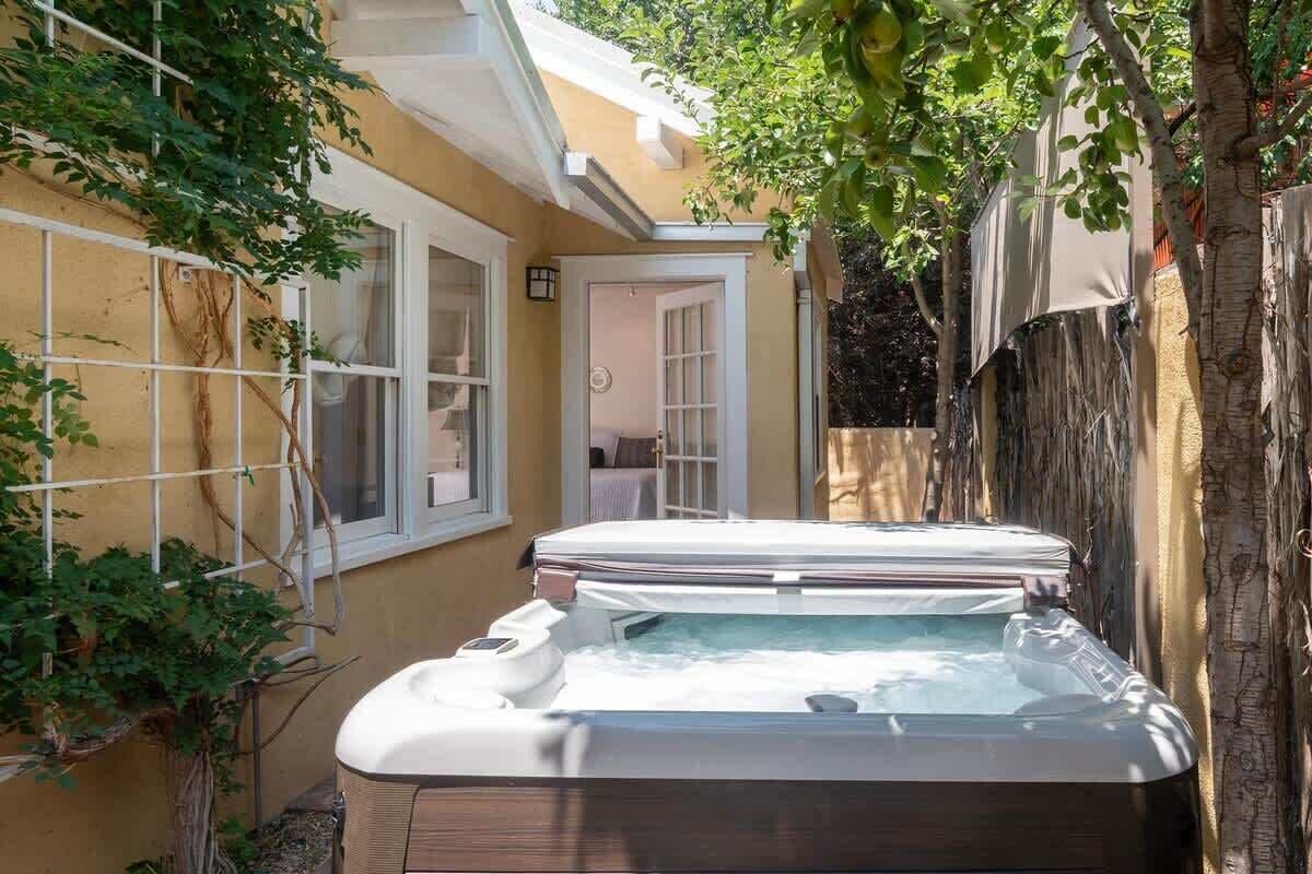 A hot tub in a backyard with a house, a window, and a door.