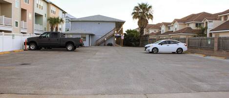 A residential area with a two-story building, a parked truck, and a white car.
