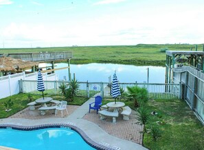Piscina com deck, cadeiras de descanso e guarda-sóis.