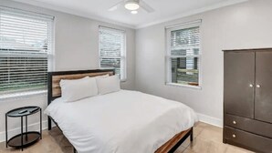 Une chambre à coucher avec un lit, un ventilateur de plafond et une armoire.
