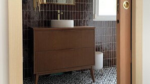 Ein Badezimmer mit einem Holzkosmetikschrank, einem großen Spiegel und fliesenbesetztem Boden.