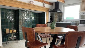 Eine moderne Küche mit einem runden Holztisch, braunen Ledersesseln und einer grünen Dekovase.