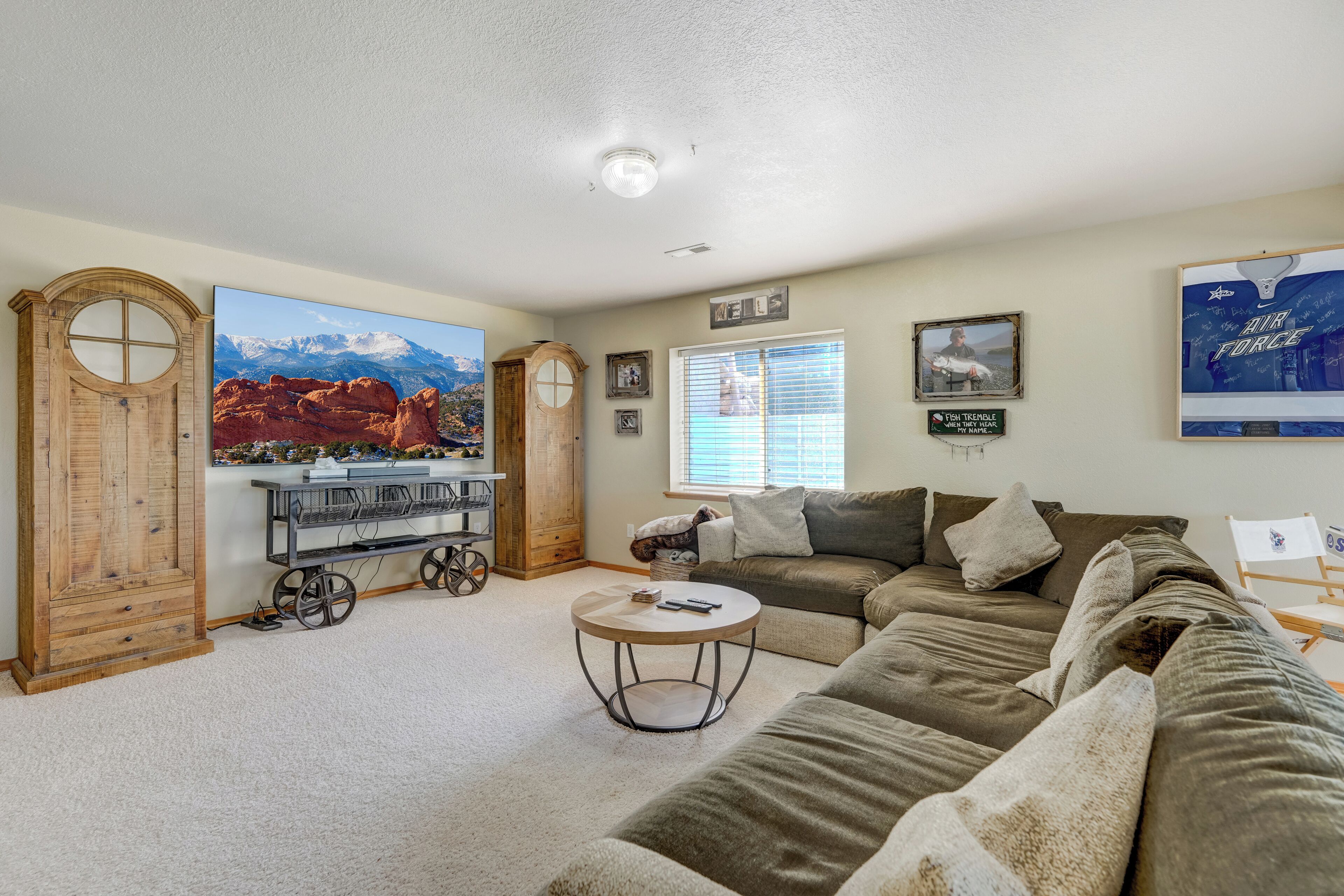 A living room with a large window, a sofa, a coffee table, and a wooden cabinet.
