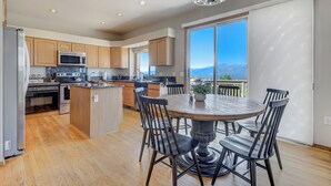 Una cocina moderna con armarios de madera, una isla central y un comedor con una mesa redonda y sillas.