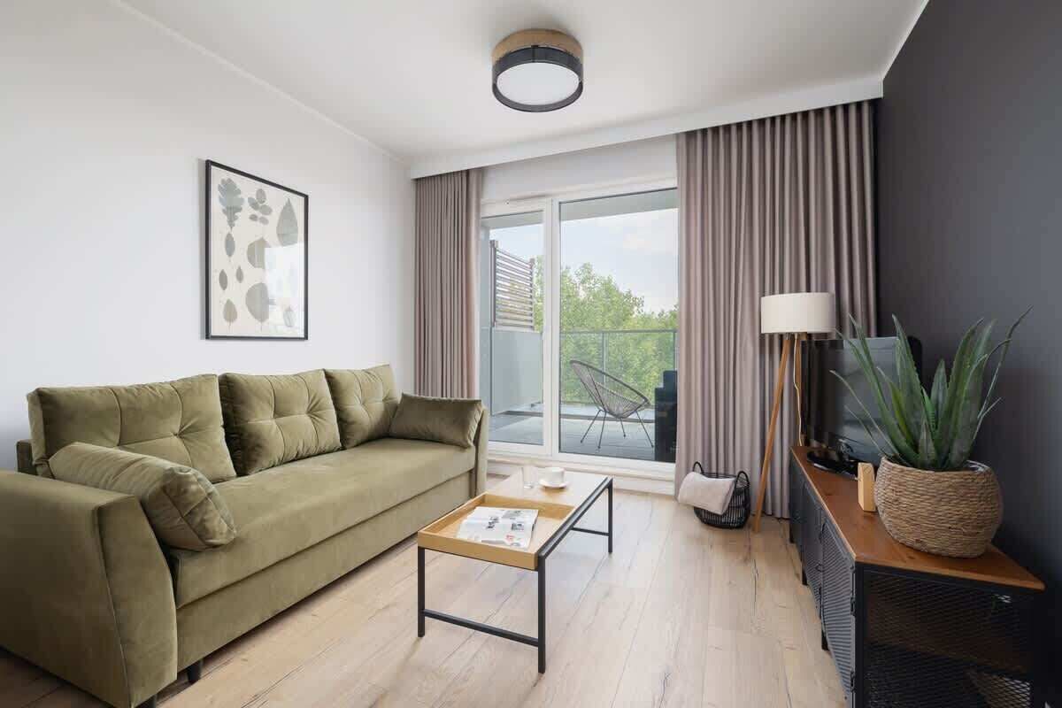 A modern living room with a sofa, a coffee table, a lamp, and a potted plant.