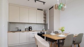 Eine moderne Küche mit weißen Schränken, einer Holzausziehtafel und einem Esstisch für vier Personen.