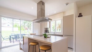 A modern kitchen with a central island, two bar stools, a large window, and a view of the outdoors. - 10 minutes from the prestigious Av de Champagne in EPERNAY, Maison à la Campagne. (Athis)
