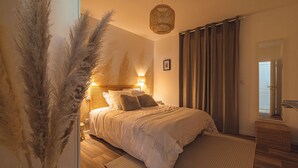 A bedroom with a bed, a bedside lamp, a hanging light fixture, a mirror, and a door. - 10 minutes from the prestigious Av de Champagne in EPERNAY, Maison à la Campagne. (Athis)