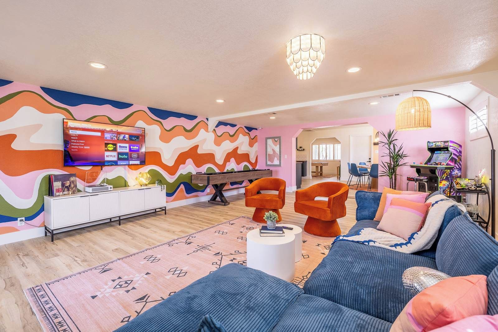Una sala de estar moderna con un llamativo diseño de pared ondulado, un televisor de pantalla plana y una zona de estar acogedora con un sofá y sillones.