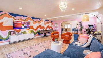 Una sala de estar moderna con un llamativo diseño de pared ondulado, un televisor de pantalla plana y una zona de estar acogedora con un sofá y sillones.