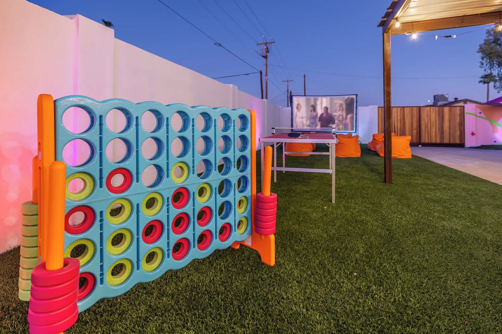 A pegboard game setup on artificial grass with a table and chairs in the background.