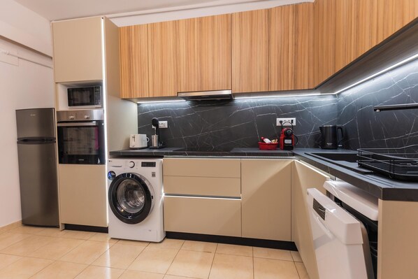 A modern kitchen with built-in appliances, wooden cabinets, and a black marble backsplash.