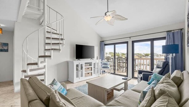 A modern living room with a spiral staircase, a flat-screen TV, a dining area, and a balcony with outdoor furniture. - Waterfront Condo Nearby Beach Boat Slip sleeps 12! (Orange Beach)