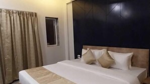 Un letto ben rifatto con testiera, una ventola a soffitto e una finestra con tende.
