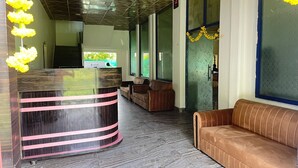 Un'area reception con una scrivania a forma di arco, un divano in pelle marrone e una porta in vetro decorata.