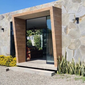 A modern building with a stone facade, a glass entrance, and a small outdoor seating area. - HOP Turquesa in Cerro Prieto (Salas)