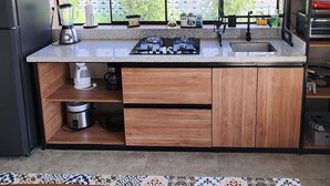 Een keuken met een granieten aanrechtblad, houten kastjes, een ingebouwde oven en een raam met uitzicht op groen.