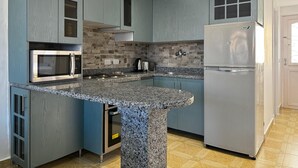 Eine moderne Küche mit Granit Arbeitsplatten, Edelstahlgeräten und blauen Schränken.