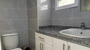 Ein Badezimmer mit Toilette, Waschbecken und Schränken.