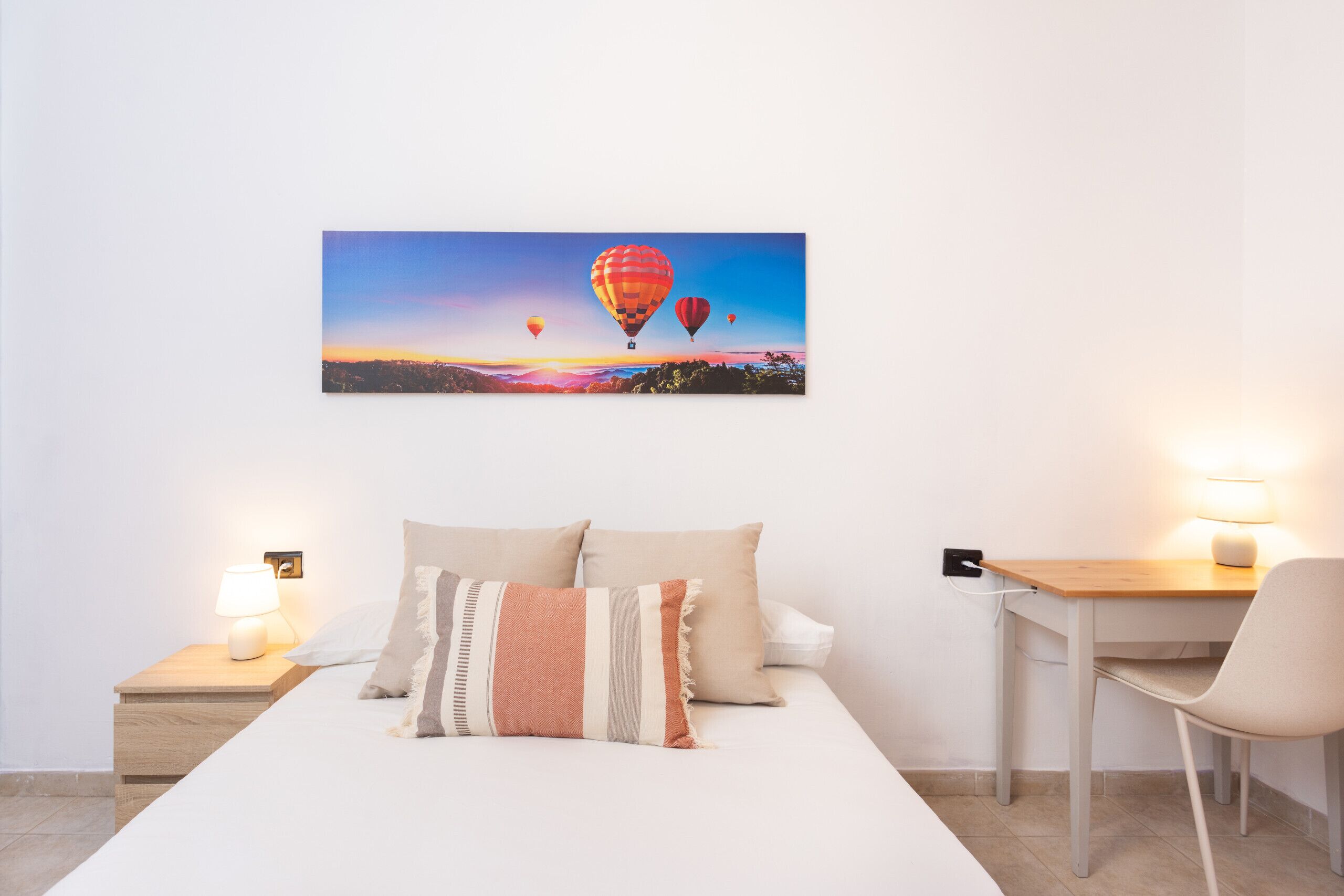 Une chambre bien rangée, avec un lit, des tables de chevet, un bureau et une chaise.