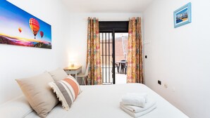 Habitación de hotel con cama, almohadas, un cuadro, un escritorio y vistas al exterior.
