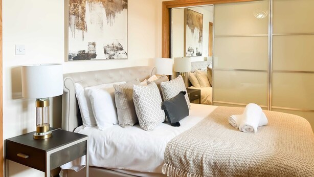 A modern hotel room with a large bed, a nightstand, a desk, and a large mirror. - Great George Lane Sum (Glasgow City)