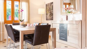 A dining area with a wooden table, black chairs, a woven pendant light, and a modern cabinet with drawers.