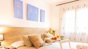 A neatly made bed with a wooden headboard, a bedside table with a lamp, and a tray with breakfast items.