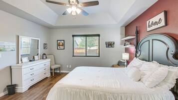 Quarto com cama, cômoda, penteadeira e ventilador de teto.