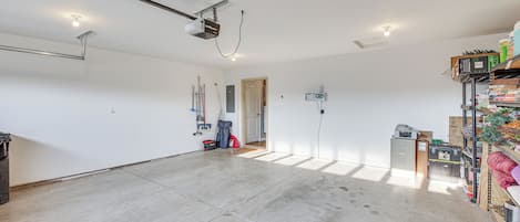 Una habitación amplia con suelo de hormigón, un proyector instalado en el techo y una puerta que da a otra zona.