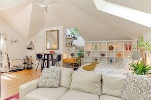 Ruime loft slaapkamer met een groot bed, een zithoek met een bank en stoelen, een bureau en een dakraam.