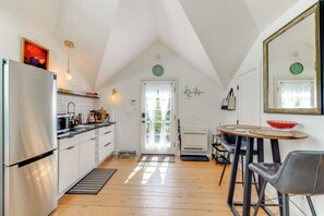 Cocina equipada con refrigerador, microondas y pileta. Hay una puerta con ventana, un espejo y un reloj en la pared.