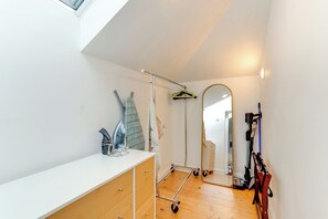 Een kleine kamer met een witte ladekast, een spiegel, een plafondventilator en een houten vloer.