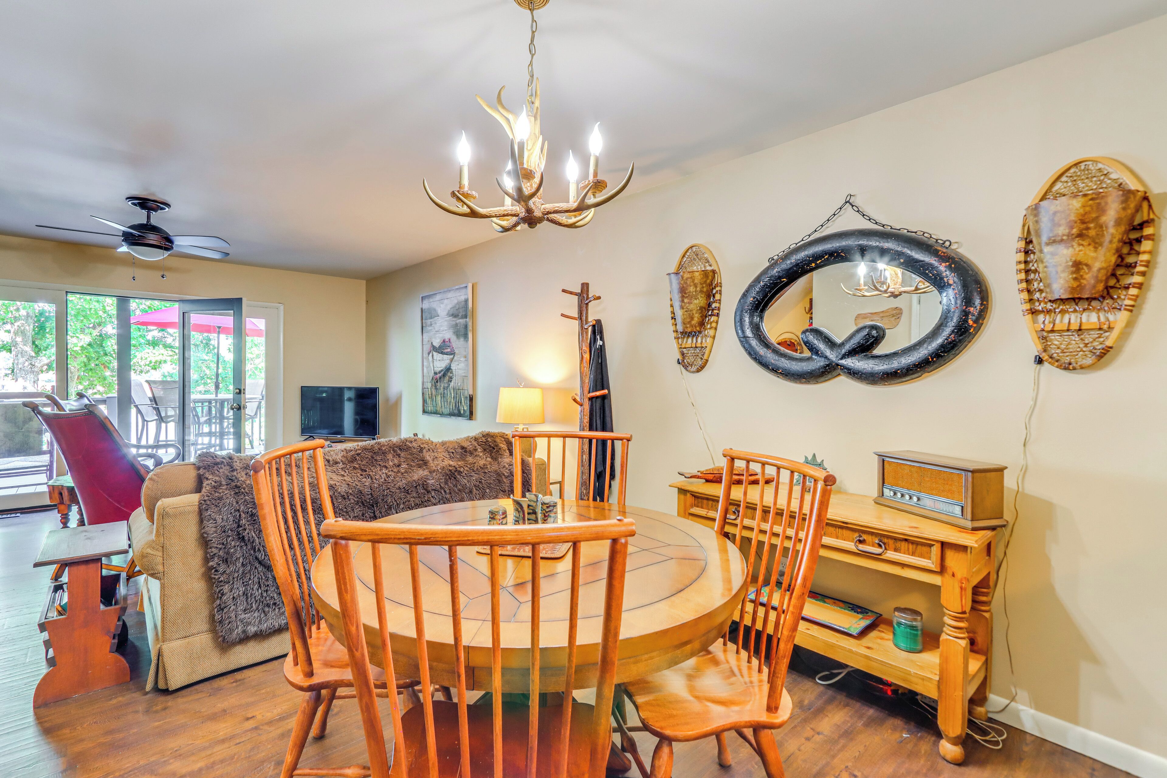 A dining area with a round wooden table and chairs, a chandelier, and a wall-mounted radio.