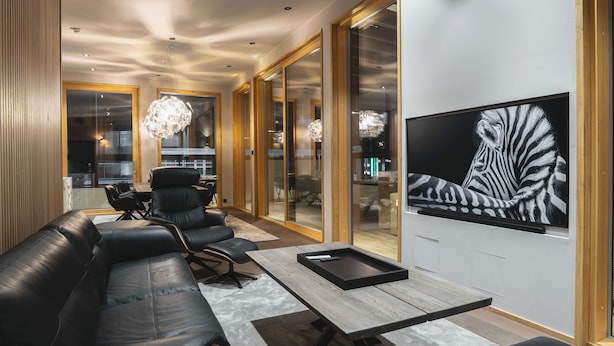 Een moderne woonkamer met een leren bank, een houten salontafel en een groot schilderij met een zebraprint op de muur.