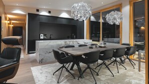 Een moderne keuken met een marmeren eiland, zwarte kasten en een eethoek met een houten tafel en zwarte stoelen.