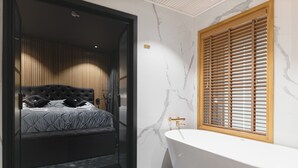 Een moderne slaapkamer met een groot bed, een inbouwkast en een vrijstaand bad.
