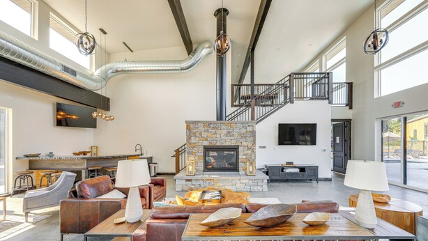 A spacious living area with a stone fireplace, leather seating, and a modern staircase. - 1 Mi to Lake: Upscale Condo in Whitefish Resort (Whitefish)