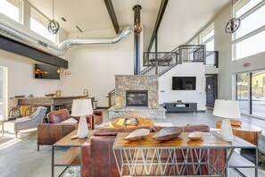 A spacious living area with a stone fireplace, leather seating, and a modern staircase. - Ski & Stroll: Condo Near Whitefish Resort (Whitefish)