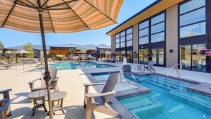 A swimming pool area with lounge chairs and a large umbrella. - 1 Mi to Lake: Upscale Condo in Whitefish Resort (Whitefish)