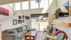 A modern living room with a grey sofa, a wooden coffee table, and a fireplace. - 1 Mi to Lake: Upscale Condo in Whitefish Resort (Whitefish)