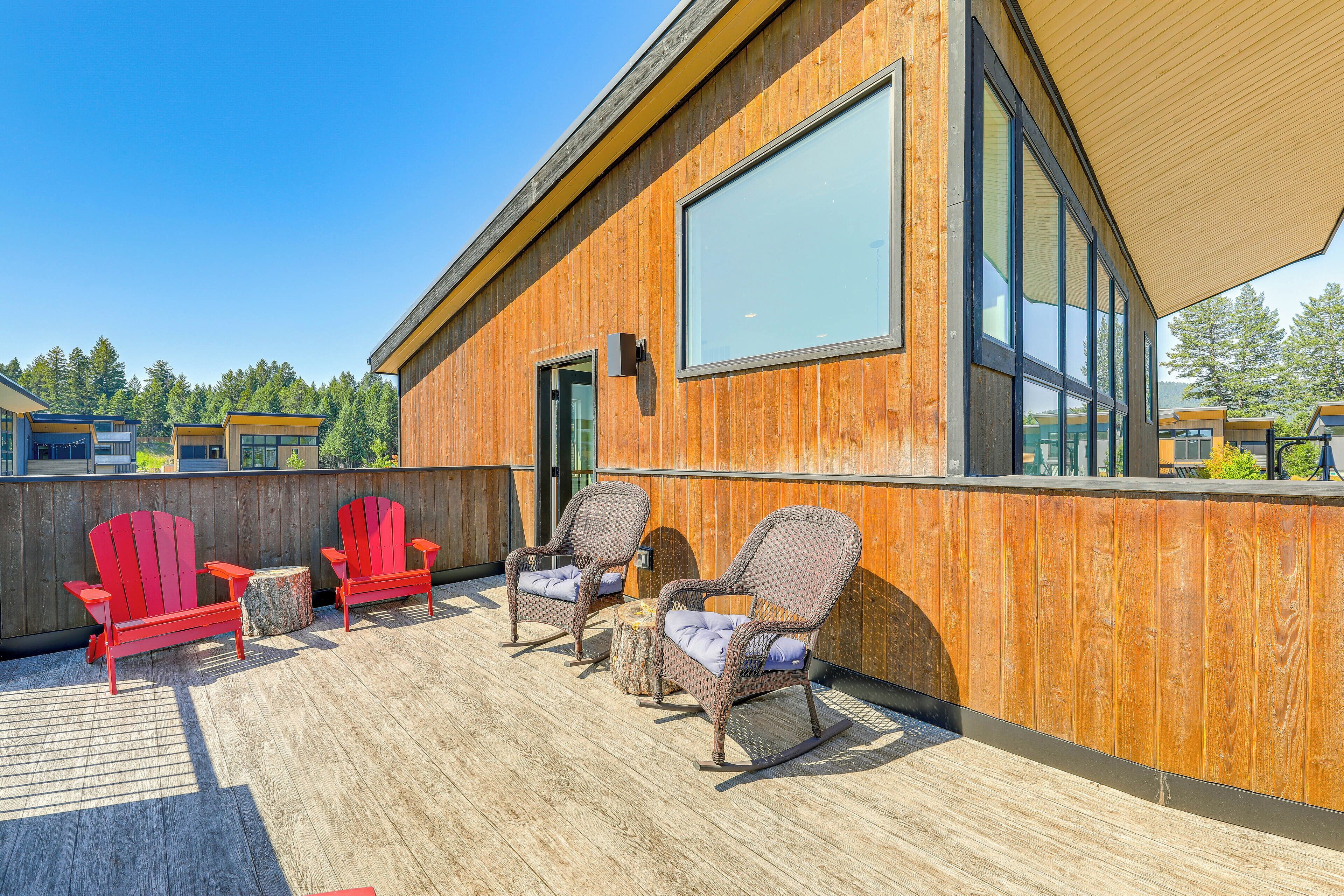 Une terrasse en bois avec deux fauteuils Adirondack et une petite table ronde.