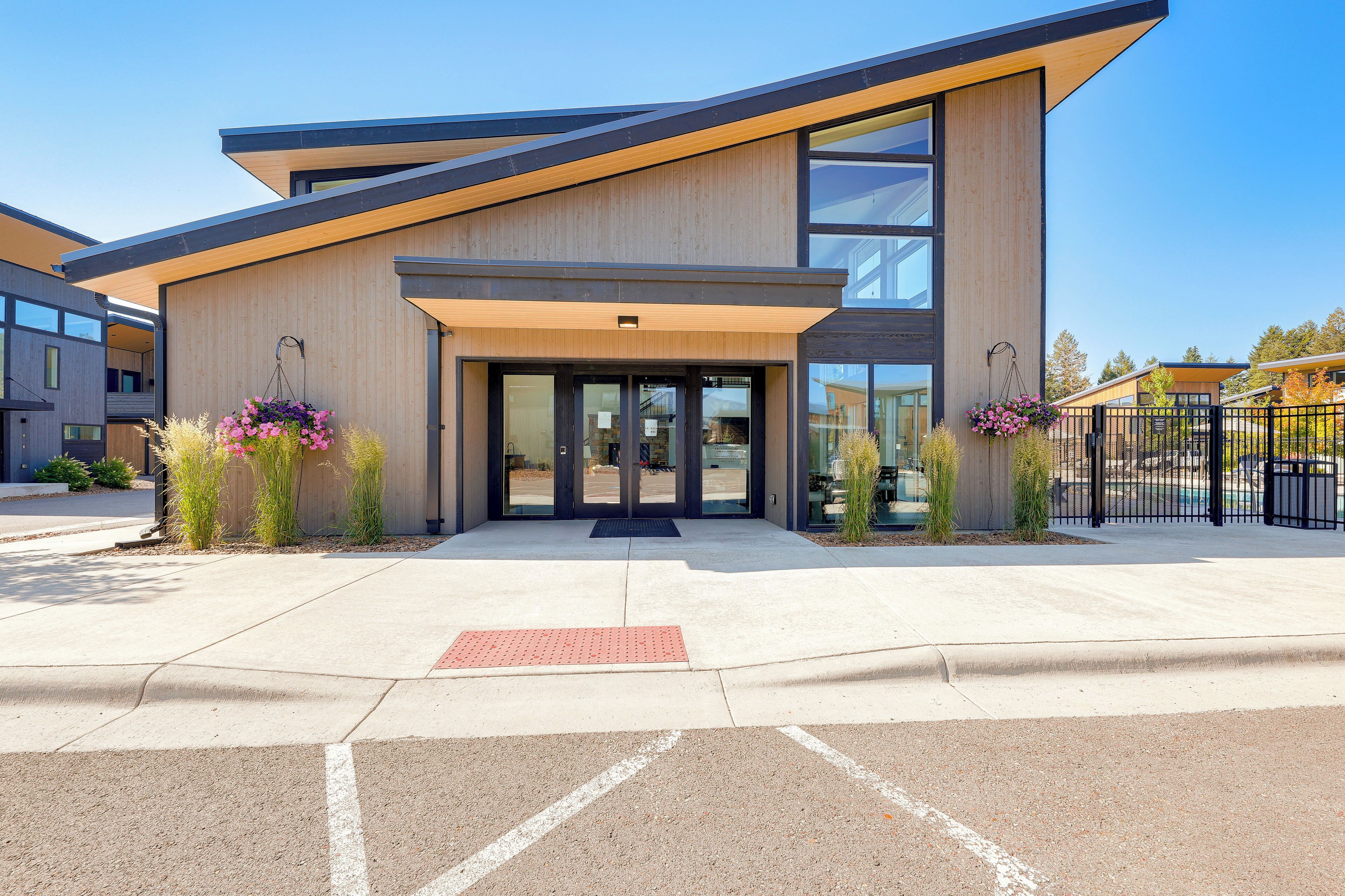 A modern building with a flat roof, large windows, and a welcoming entrance with a red tactile paving.