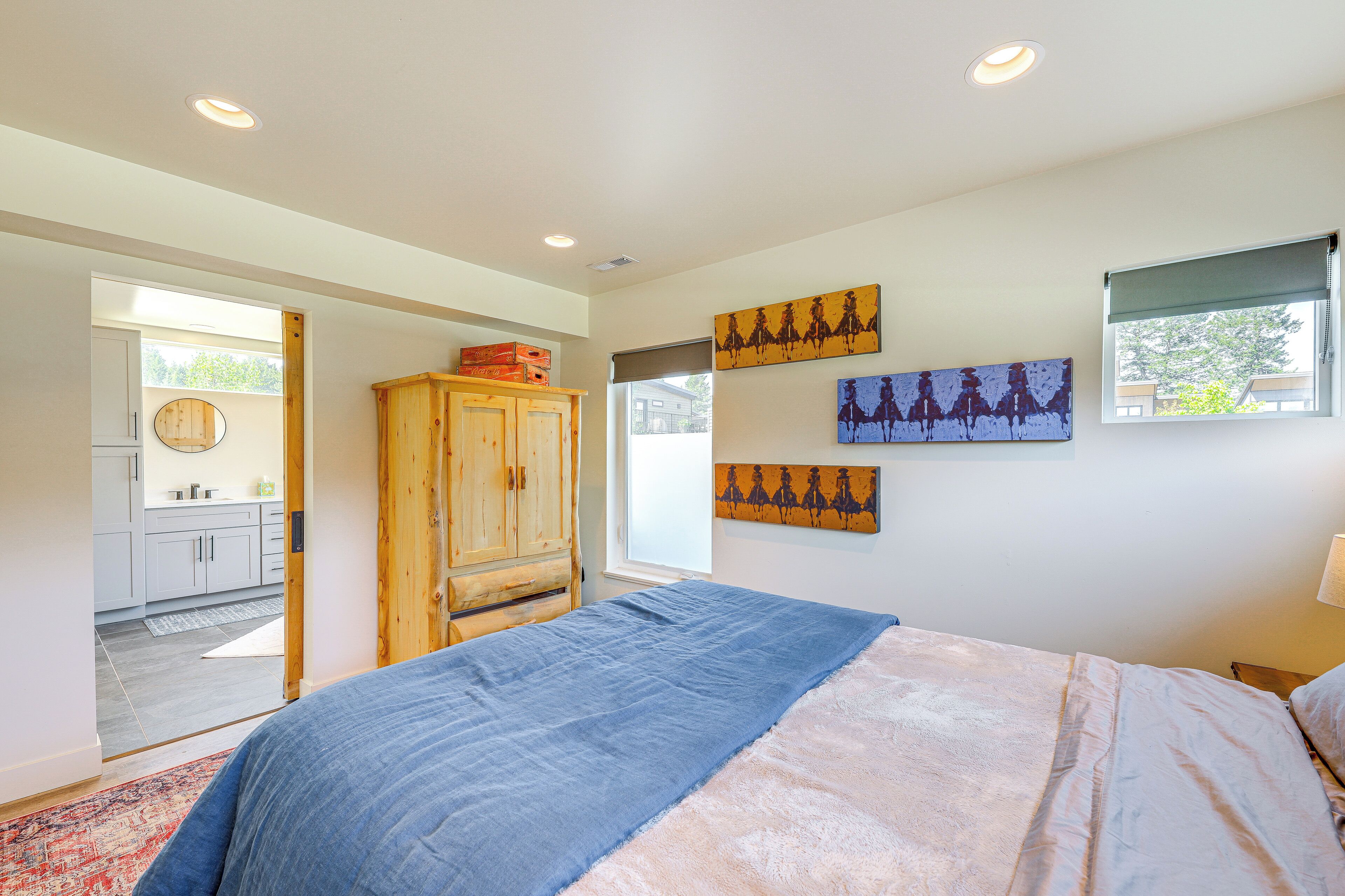 A bedroom with a bed, wooden wardrobe, and artwork on the walls.