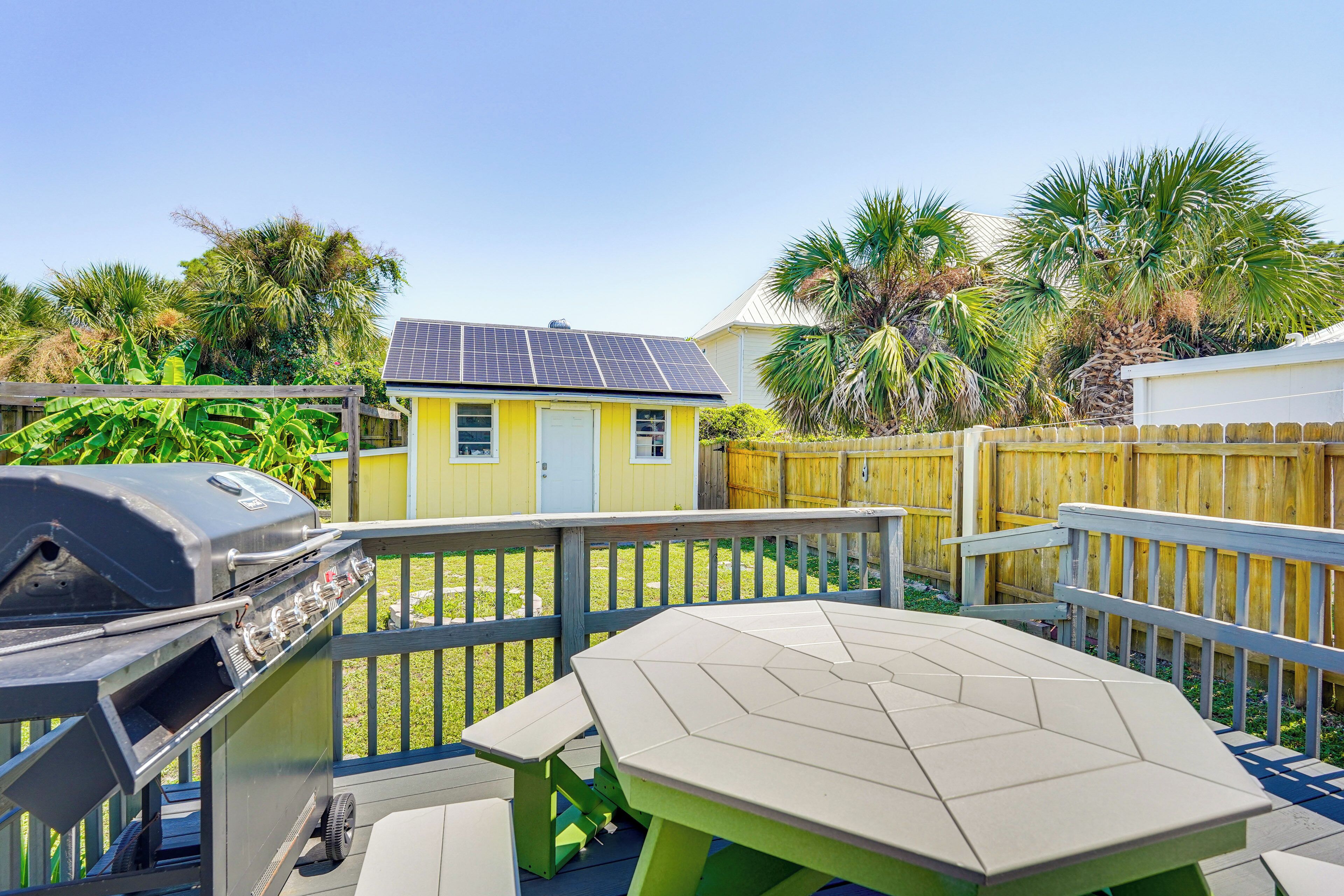 A backyard with a barbecue grill, a table, and a small house with solar panels.