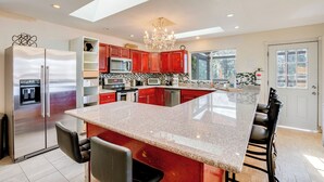A modern kitchen with a large island, stainless steel appliances, and red cabinetry. - Scenic Home w/ Sauna - 7 Mi to Heavenly Mountain! (Stateline)