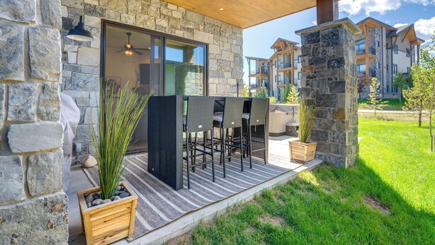 Une façade en pierre, un patio couvert, des sièges à l’extérieur et une vue sur les bâtiments voisins.