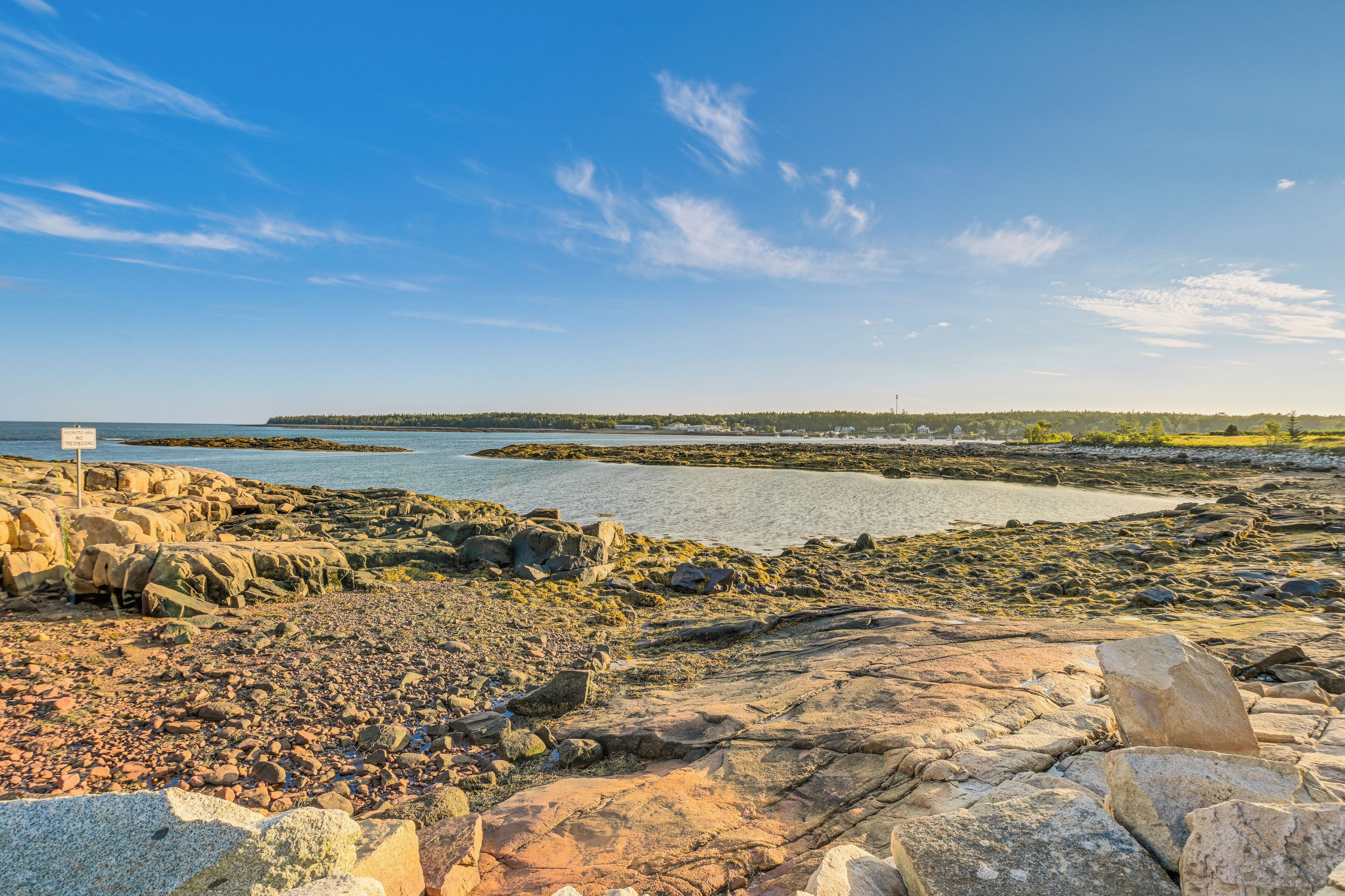 A rocky shoreline with a clear view of the sea and distant land.